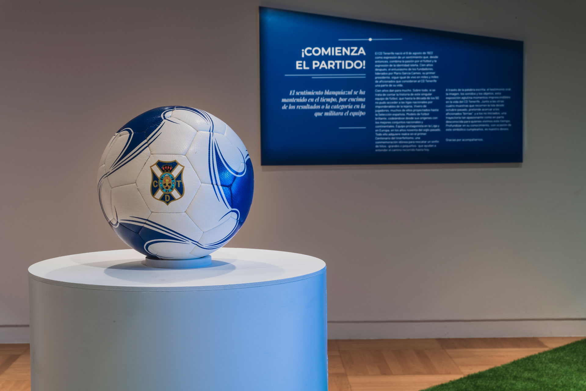 Exposición CD Tenerife: balón sobre peana en primer plano y panel introductorio en la pared del fondo.