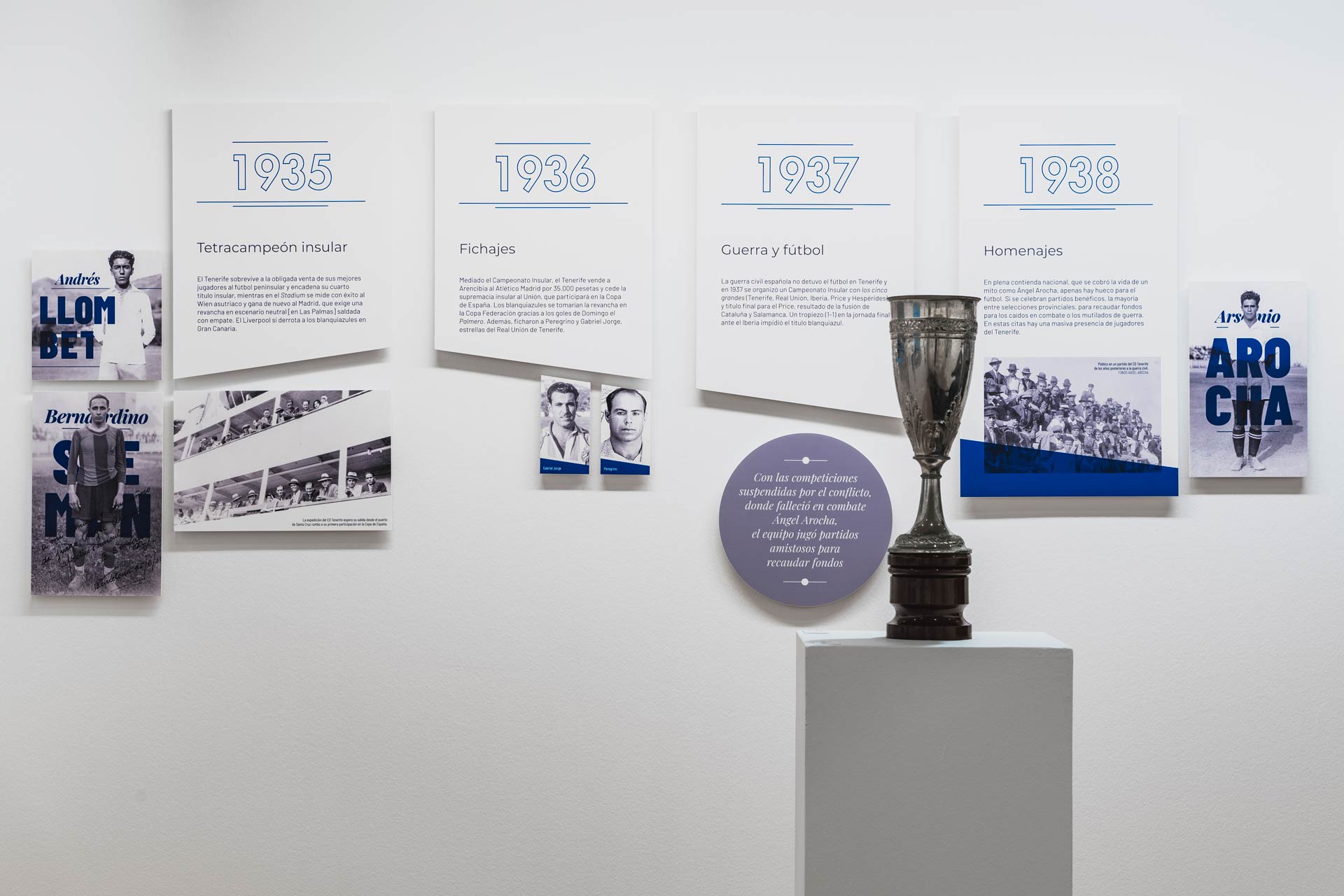 Exposición CD Tenerife: Vista frontal de pared, en ella se encuentran los paneles descriptivos de los años 1935, 1936, 1937 y 1938, acompañados de algunas fotos en blanco y negro así como de un trofeo de la época.